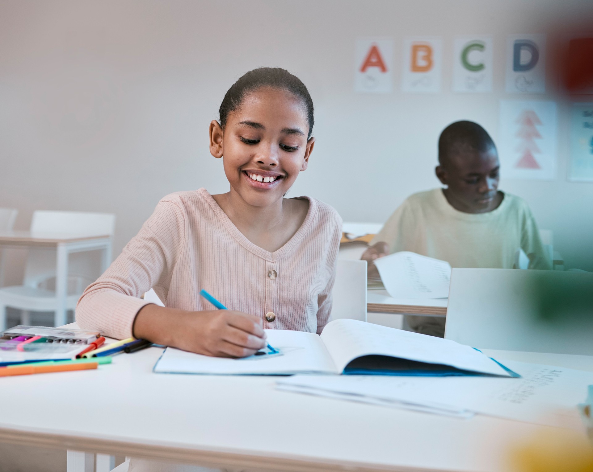 Education, smile and child in classroom learning reading, writing and math in Montessori school in New York. Books, students and happy girl at kid desk in class with notebook studying for future exam