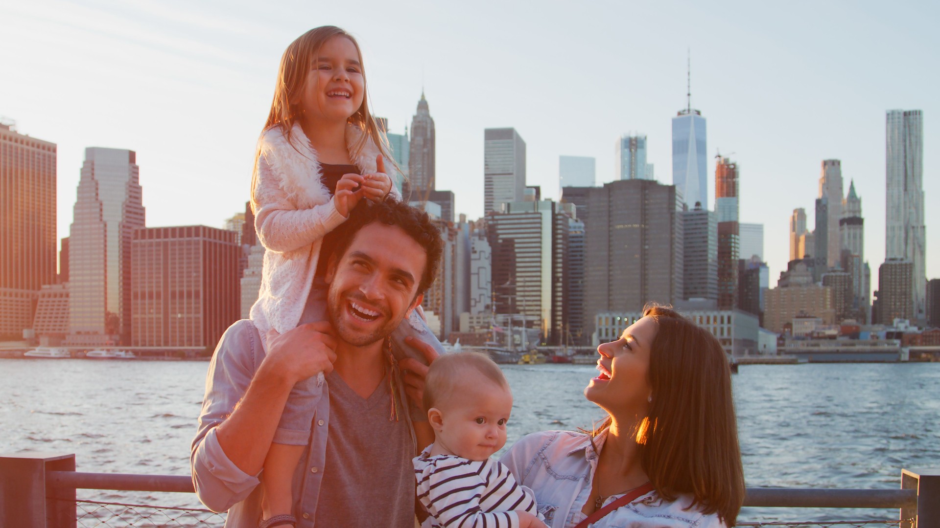 Family Day Out With Parents And Children Standing In Front Of Manhattan Skyline In New York City USA